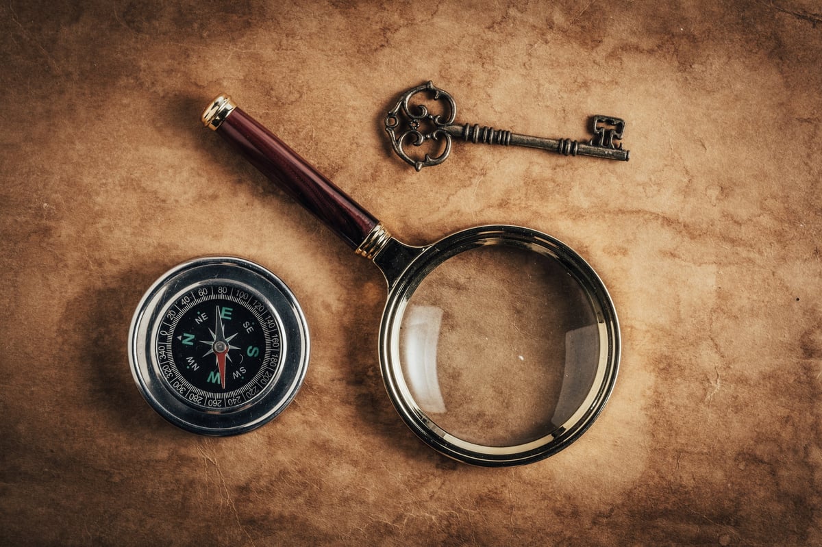 Vintage compass, key and magnifying glass on aged paper background